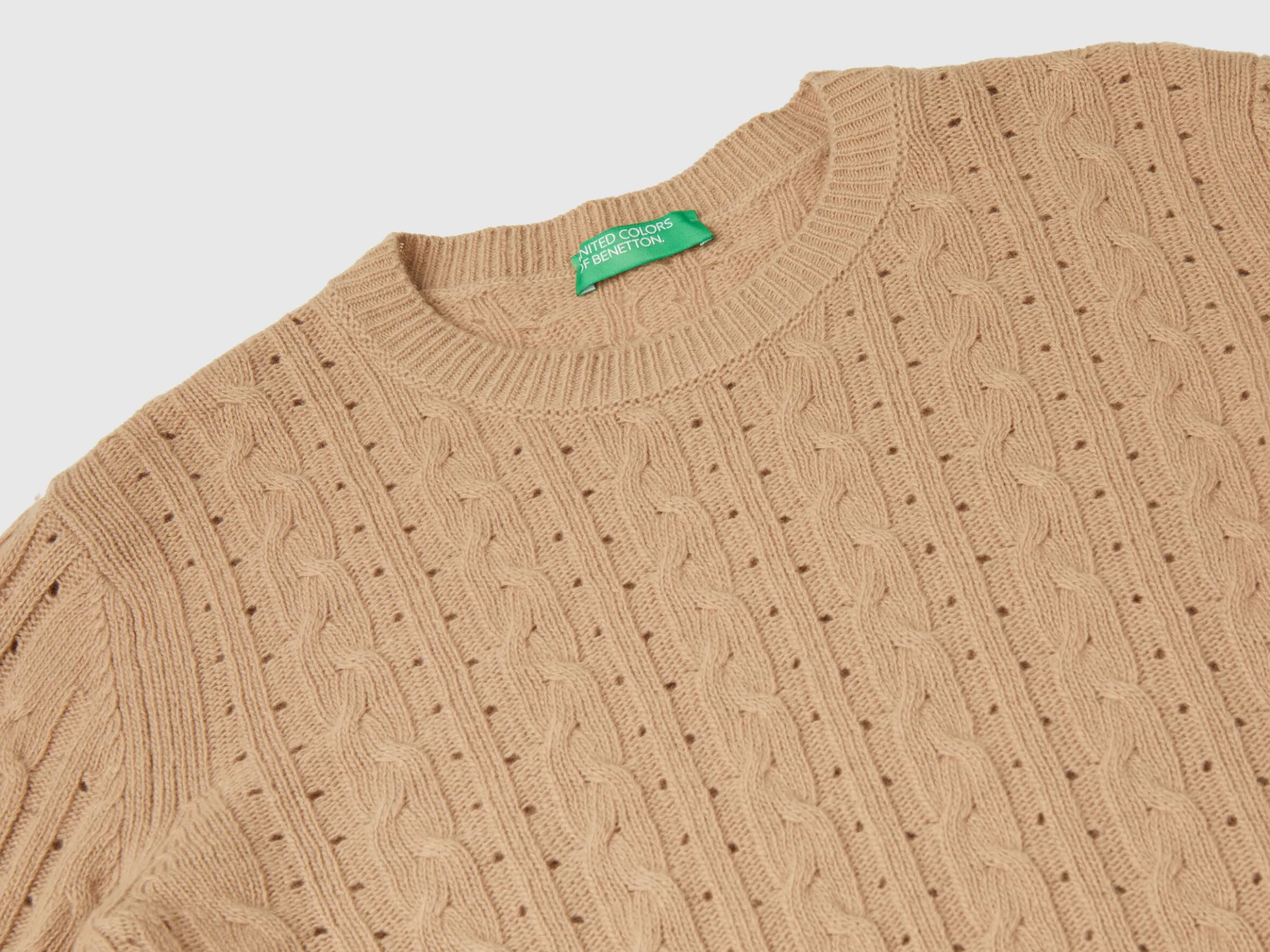 Cropped sweater with cable knit and perforations