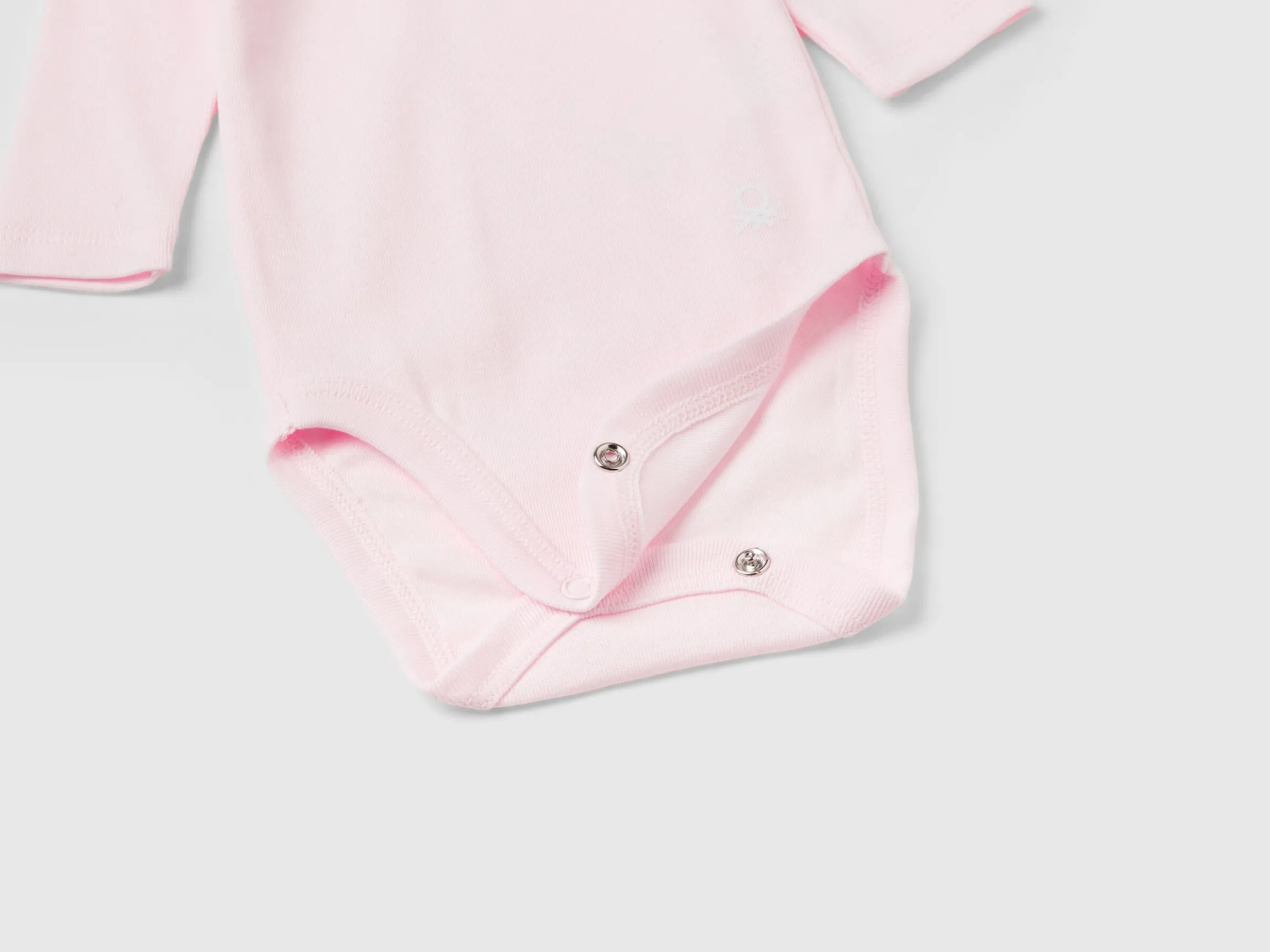 Three solid color bodysuits in organic cotton